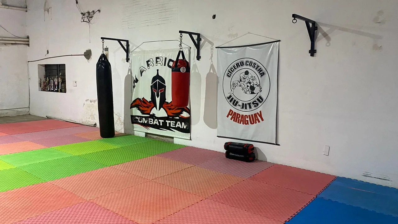 El tatami de Warriors Combat Team en Luque, con los banderines de la academia y de Cicero Costha Jiu-Jitsu Paraguay